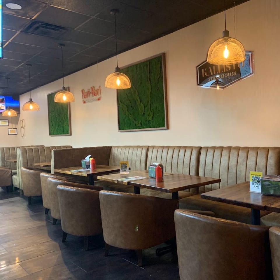 Interior of Peri Peri Original & Kallisto Steakhouse with brown booths, tables, and hanging lights.